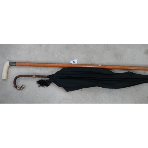 87 - An old umbrella with 19th century mounts (a/f) and a walking stick with silver mounts.