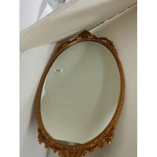 185 - A gilt metal framed oval mirror, in good condition.