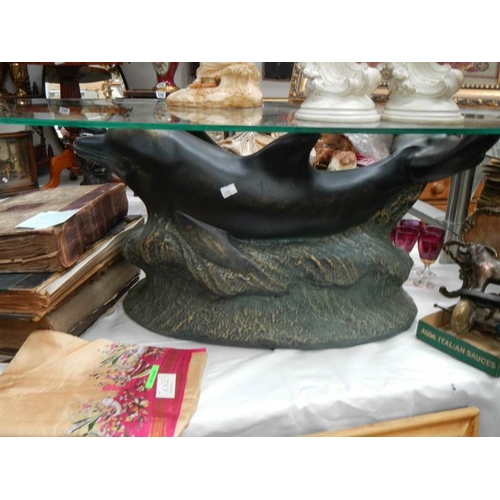 212 - A mid 20th century glass top table with dolphin base, 48'' wide and 15'' tall.