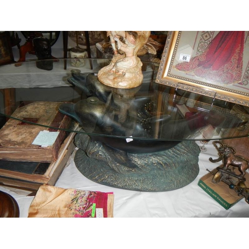 212 - A mid 20th century glass top table with dolphin base, 48'' wide and 15'' tall.