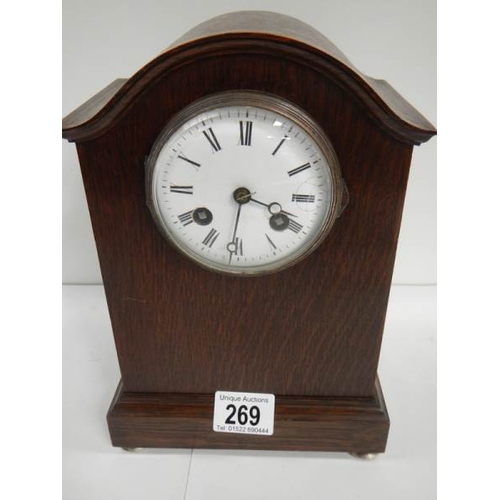 269 - An oak mantel clock in working order complet with key and pendulum (chip on face)