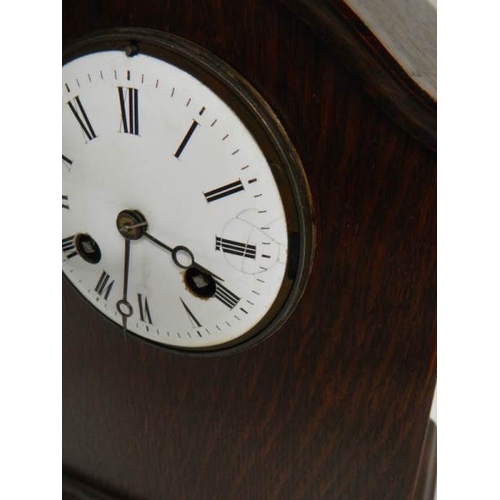 269 - An oak mantel clock in working order complet with key and pendulum (chip on face)