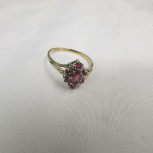 2104 - A ruby and diamond cluster ring with gold openwork shoulders, size R.