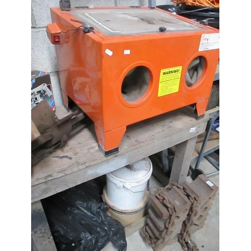 1023 - A cabinet sandblaster with various grades of blast media and a bench