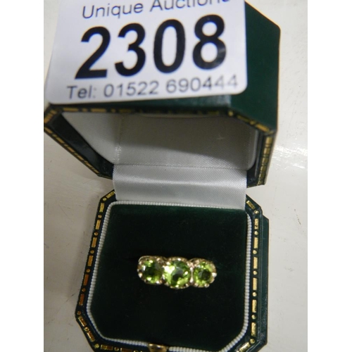 2308 - A stunning deep coloured peridot three stone ring dated London 1972 with a fancy gold work mount in ... 