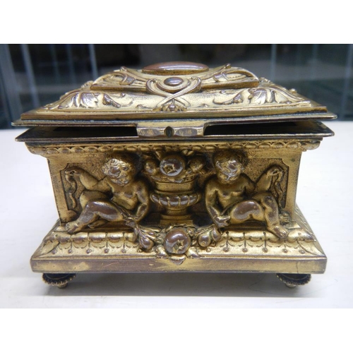 2318 - A 19th century gilded bronze casket with frolicking cherubs beside urns, silk lines.