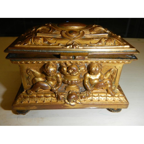 2318 - A 19th century gilded bronze casket with frolicking cherubs beside urns, silk lines.