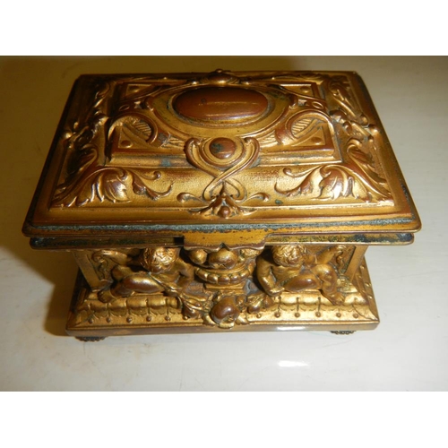 2318 - A 19th century gilded bronze casket with frolicking cherubs beside urns, silk lines.