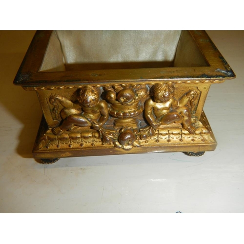 2318 - A 19th century gilded bronze casket with frolicking cherubs beside urns, silk lines.