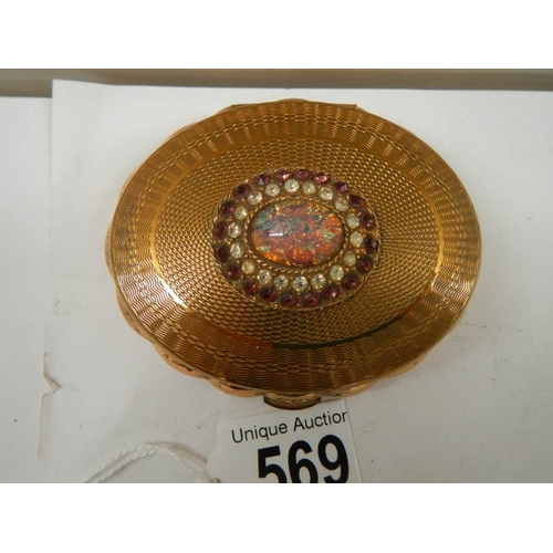 569 - A 1950's oval powder compact with jeweled top, in good condition.