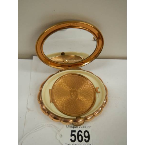 569 - A 1950's oval powder compact with jeweled top, in good condition.