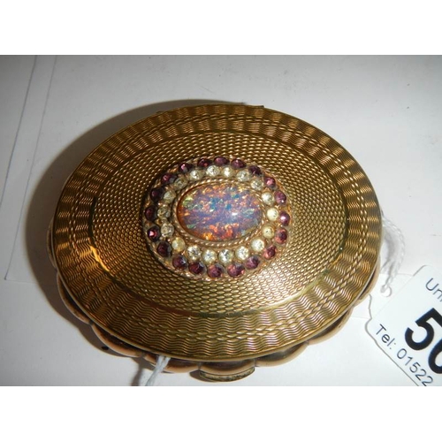 569 - A 1950's oval powder compact with jeweled top, in good condition.