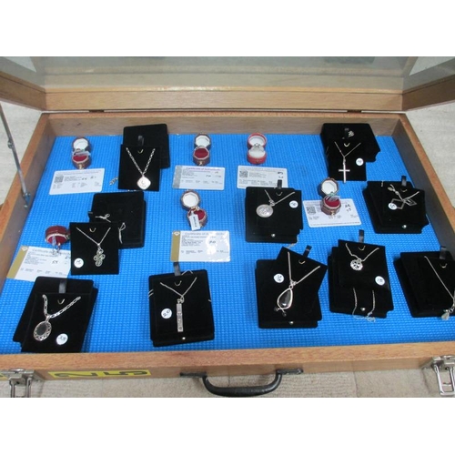 656 - A display case containing 6 silver rings, all with certificates, and 10 silver pendants.