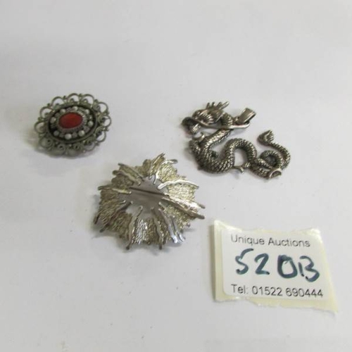 520B - A silver dragon pendant and 2 silver brooches one set with coral stone.