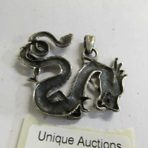 520B - A silver dragon pendant and 2 silver brooches one set with coral stone.