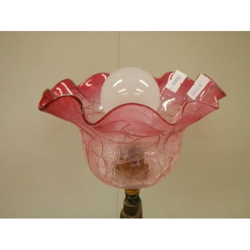 770 - A bronzed effect figure group table lamp with cranberry glass shade.