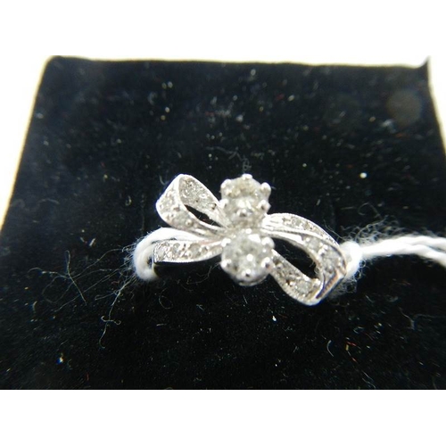 2024 - An 18ct white gold and diamond bow ring.  Size K.