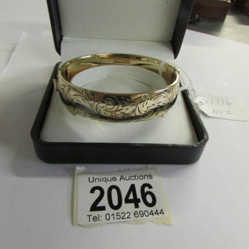 2046 - A circa 1970/80's, 9ct gold on a metal engraved bangle.