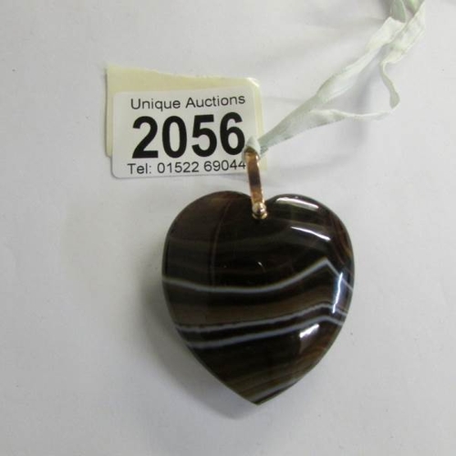 2056 - A banded agate heart shaped pendant with a rose gold 9ct loop on a silk ribbon.