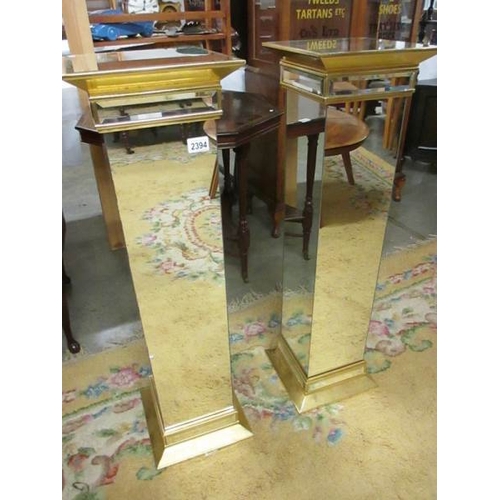 2394 - A pair of bevelled mirrored glass pedestals, 39'' tall.