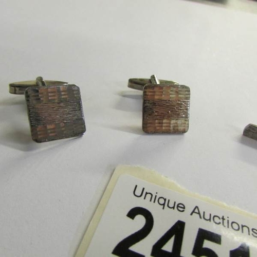 2451 - A pair of silver cuff links and a matching silver tie pin.