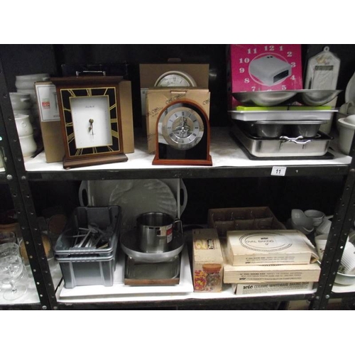 11 - 2 shelves of kitchen ware and 4 good boxed unused battery clocks.