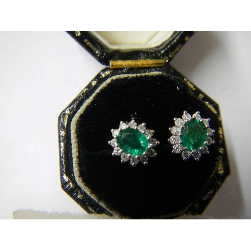 1026 - A pair of 18ct white gold 1ct emerald and diamond ear studs.