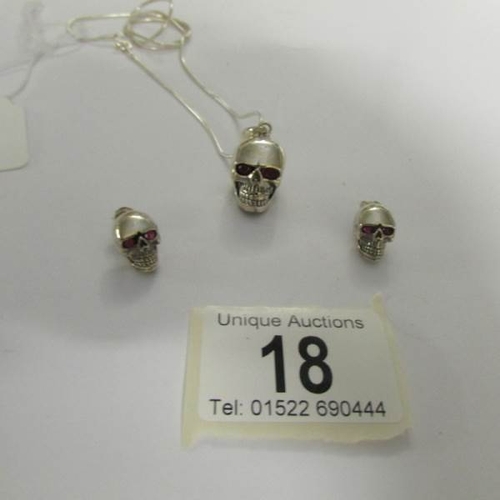 18 - A silver skull pendant and matching earrings with ruby eyes.