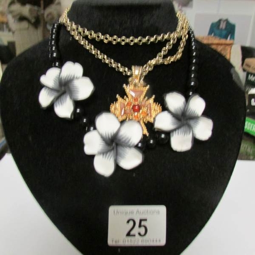 25 - A black and white necklace together with another necklace on stand.