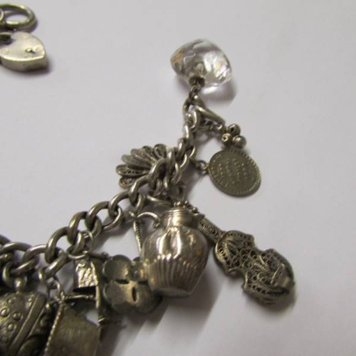 41 - A vintage charm bracelet with a variety of mostly silver charms, some opening, one for Chester, enam... 