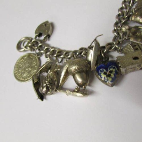 41 - A vintage charm bracelet with a variety of mostly silver charms, some opening, one for Chester, enam... 