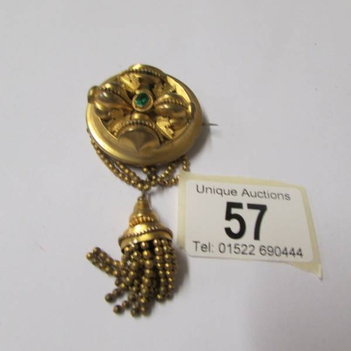 57 - A Victorian brooch set with a green stone having tassel drops in yellow metal.