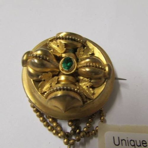 57 - A Victorian brooch set with a green stone having tassel drops in yellow metal.