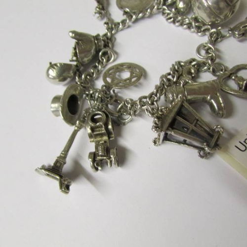 8 - A silver charm bracelet with 15 interesting charms, four open, a boxing glove, vintage car, boat etc... 