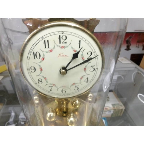 135 - A brass anniversary clock under glass dome.