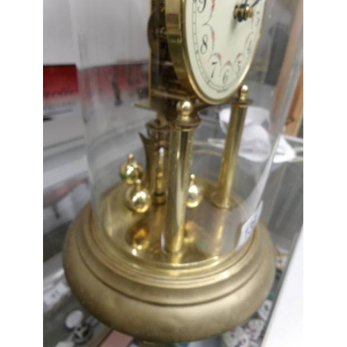 135 - A brass anniversary clock under glass dome.