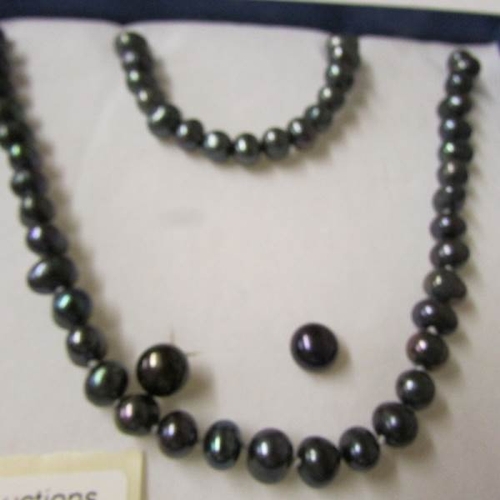 66 - A black pearl necklace, bracelet and earrings.