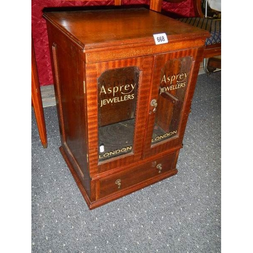 668 - A mahogany glazed two door display cabinet with drawers with Asprey's advertising glazed panels.