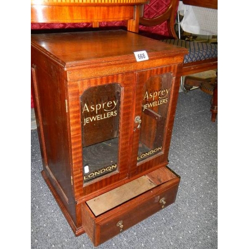 668 - A mahogany glazed two door display cabinet with drawers with Asprey's advertising glazed panels.