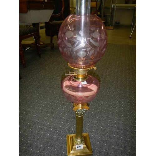 675 - A Brass Corinthian column oil lamp with cranberry cut glass font and shade.