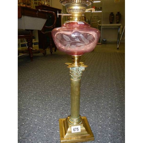 675 - A Brass Corinthian column oil lamp with cranberry cut glass font and shade.