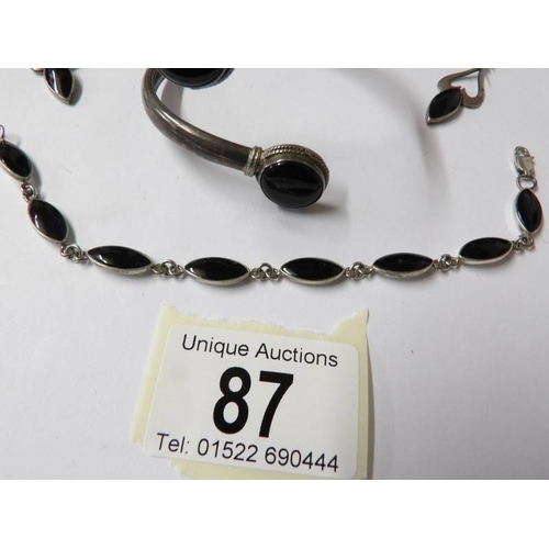 87 - A silver and onyx bangle, bracelet and earrings.