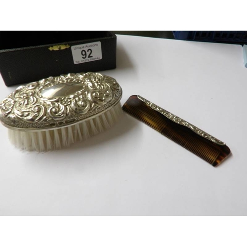 92 - A cased silver backed hair brush and comb.