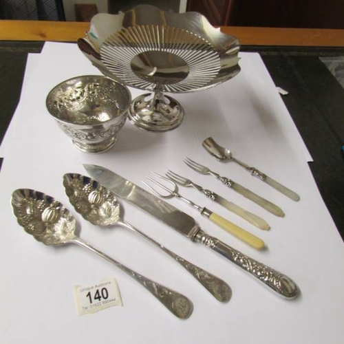 140 - A small embossed silver bowl (67 grams), a silver plate comport, a pair of silver plate berry spoons... 