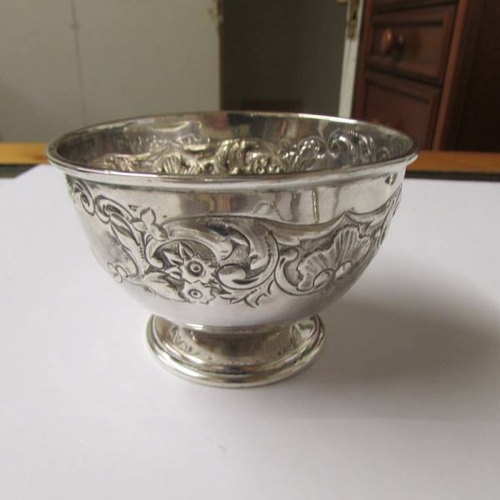 140 - A small embossed silver bowl (67 grams), a silver plate comport, a pair of silver plate berry spoons... 