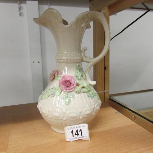 141 - A Belleek jug decorated with applied roses, 23 cm tall.