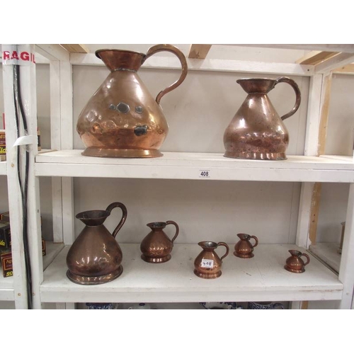 408 - A set of seven graduated copper ale jugs