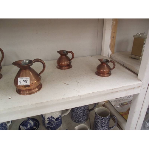 408 - A set of seven graduated copper ale jugs