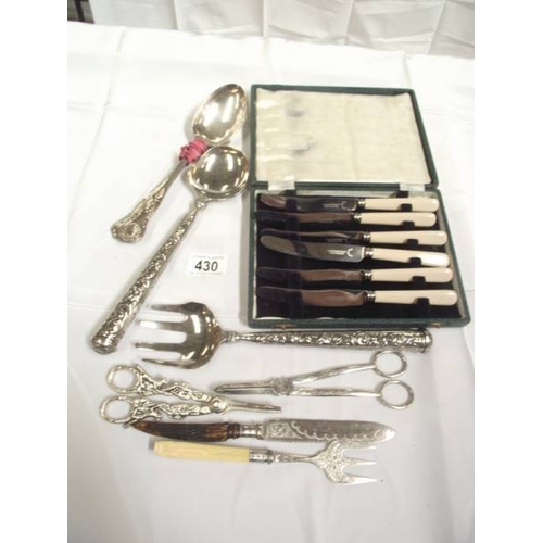 430 - A cased set of butter knives, salad servers, serving spoons, grape scissors etc.