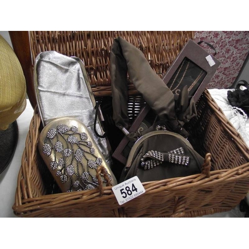 584 - A wicker basket containing vintage evening bags etc.,